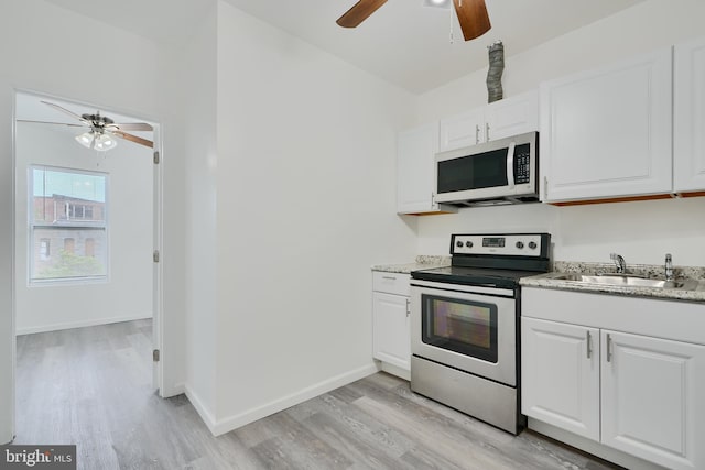 kitchen featuring white microwave, stainless steel electric range, a ceiling fan, light wood-type flooring, and a sink