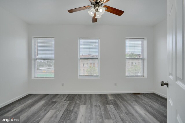 empty room featuring wood finished floors, a ceiling fan, and baseboards