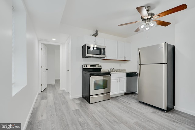 kitchen featuring appliances with stainless steel finishes, light wood finished floors, white cabinets, and a ceiling fan