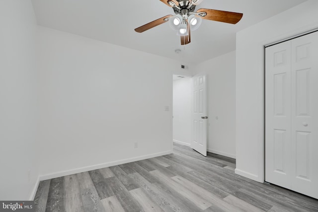 unfurnished bedroom featuring wood finished floors, baseboards, a closet, and ceiling fan