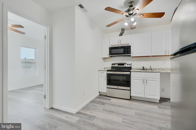kitchen with stainless steel appliances, ceiling fan, light wood finished floors, white cabinets, and a sink