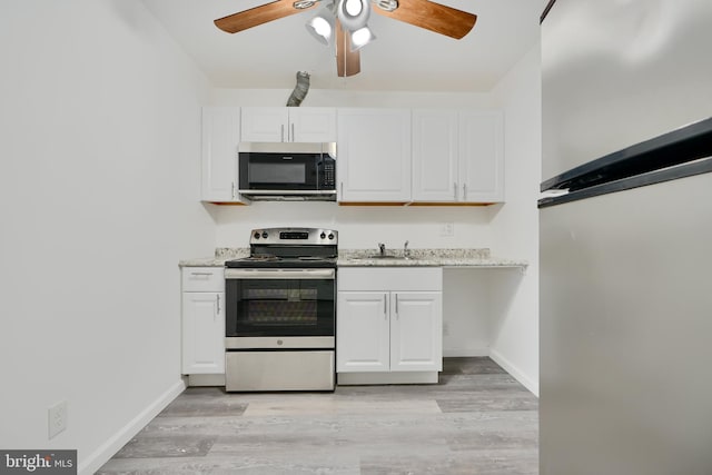 kitchen with appliances with stainless steel finishes, white cabinets, ceiling fan, light wood finished floors, and light stone counters