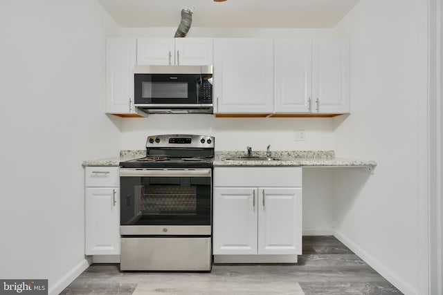 kitchen featuring appliances with stainless steel finishes, baseboards, white cabinets, and light wood-type flooring