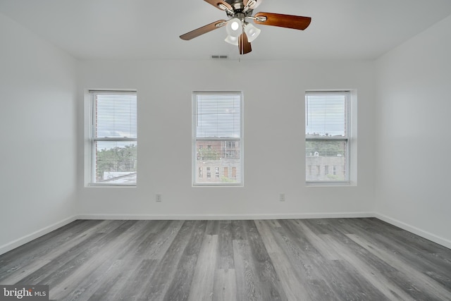 empty room with wood finished floors, a ceiling fan, and baseboards