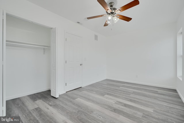 unfurnished bedroom with wood finished floors, baseboards, a closet, and a ceiling fan