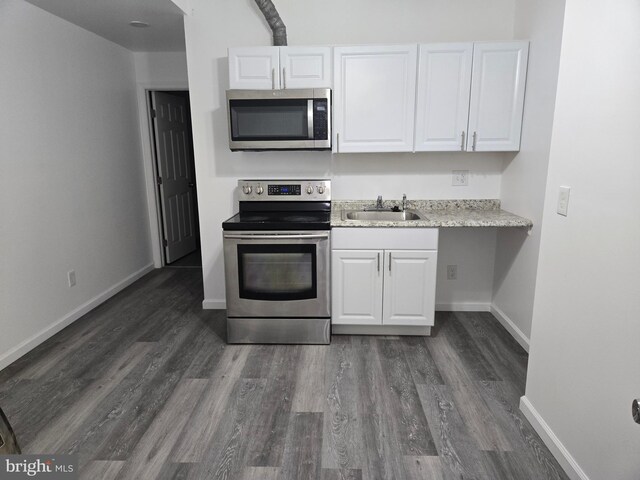 kitchen with stainless steel appliances, a sink, white cabinetry, and dark wood-style floors