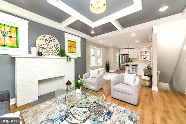 living area featuring coffered ceiling, a chandelier, light wood-type flooring, baseboards, and a fireplace with flush hearth