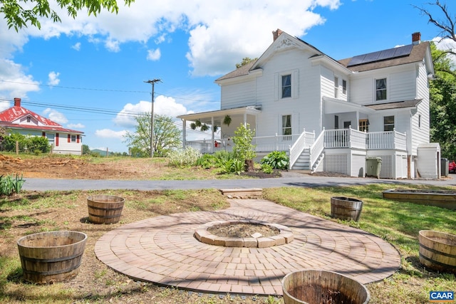 2010 White Bridge Rd, Waynesboro, VA 22980 - back of house featuring a fire pit, roof mounted solar panels, a chimney, stairs, and a porch