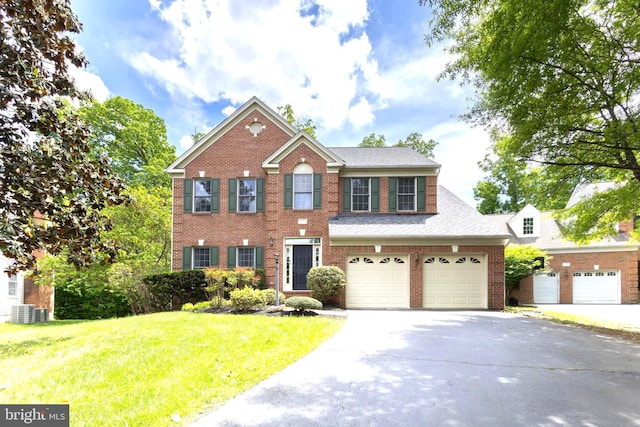 12685 Fox Woods Dr, Herndon, VA 20171 - view of front facade with concrete driveway, a front yard, cooling unit, brick siding, and an attached garage