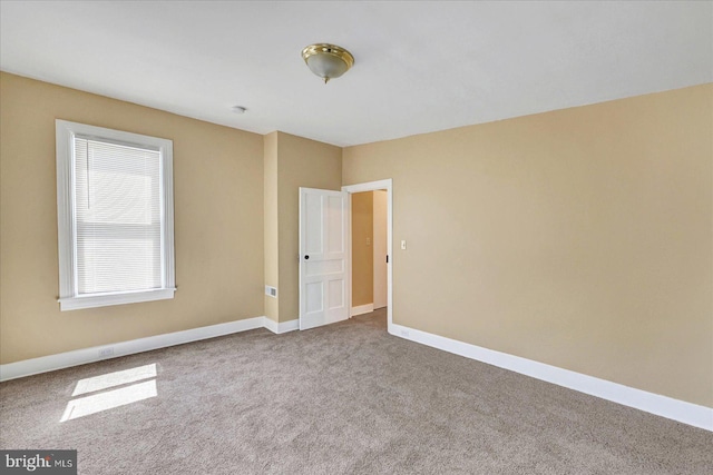 spare room featuring carpet flooring and baseboards