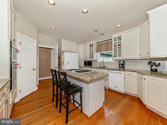 16013 Pheasant Ridge Ct, Woodbine, MD 21797 - kitchen with white appliances, a kitchen breakfast bar, a kitchen island, a sink, and light wood-type flooring
