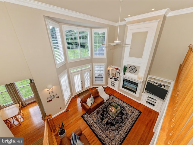 16013 Pheasant Ridge Ct, Woodbine, MD 21797 - living room featuring wood finished floors, a towering ceiling, ornamental molding, french doors, and a glass covered fireplace