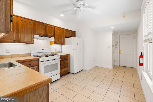 kitchen with white appliances, under cabinet range hood, recessed lighting, light countertops, and brown cabinetry