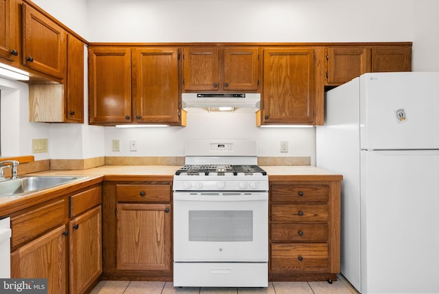 kitchen with white appliances, under cabinet range hood, a sink, and light countertops