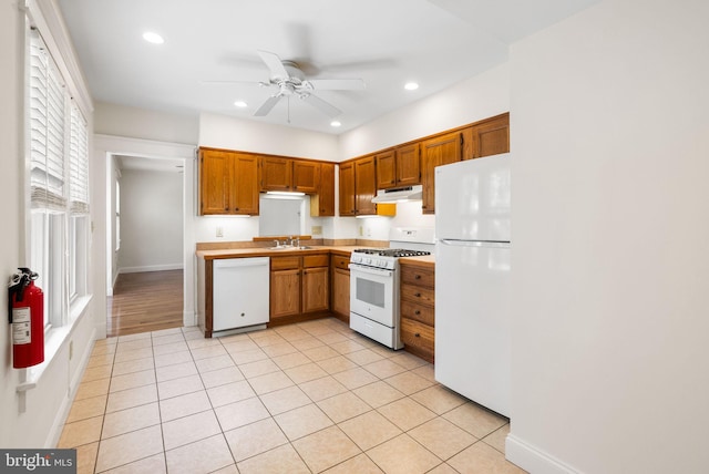 kitchen with white appliances, under cabinet range hood, a sink, ceiling fan, and light countertops