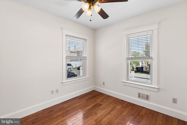 spare room with healthy amount of natural light, baseboards, wood finished floors, and a ceiling fan