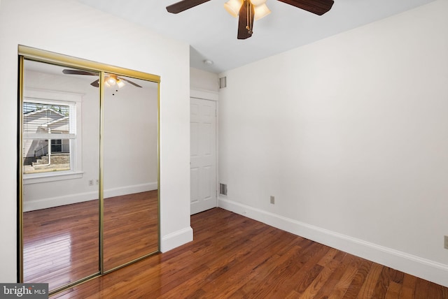 unfurnished bedroom featuring wood finished floors, baseboards, a closet, and ceiling fan