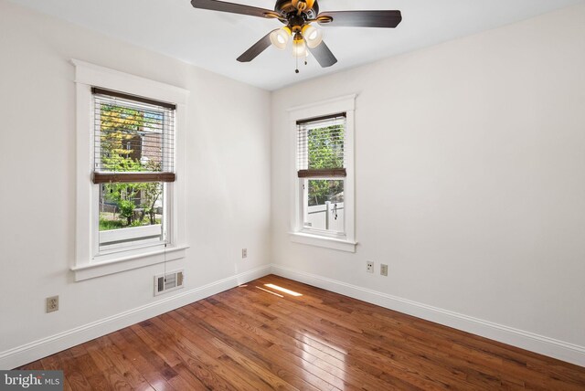 unfurnished room featuring hardwood / wood-style floors, baseboards, and a ceiling fan