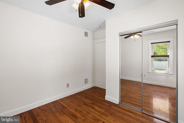 unfurnished bedroom with wood finished floors, baseboards, a closet, and a ceiling fan