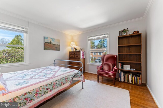 bedroom with crown molding, wood finished floors, and baseboards
