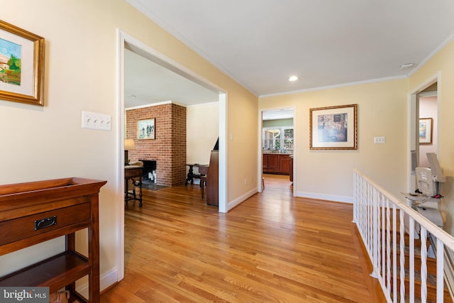 hall with light wood-style flooring, ornamental molding, baseboards, and recessed lighting