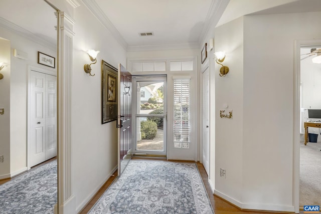 doorway with ornamental molding, baseboards, and wood finished floors