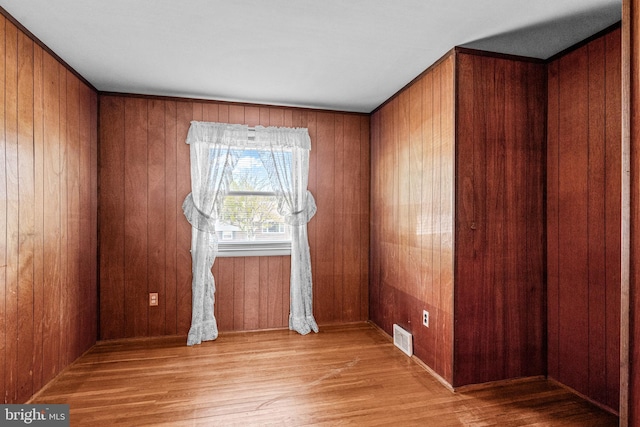 unfurnished room featuring wood finished floors and wooden walls
