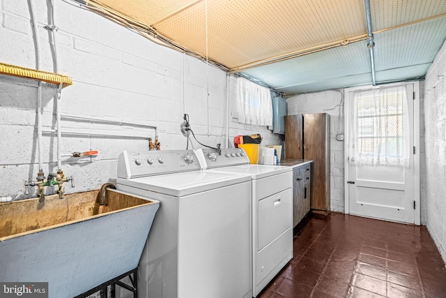 laundry room featuring washing machine and clothes dryer, cabinet space, and concrete block wall