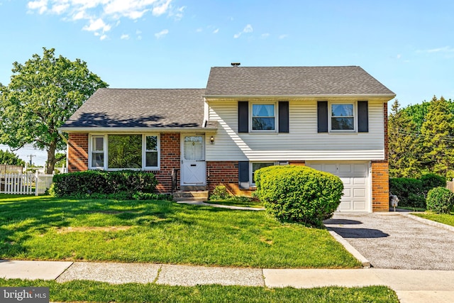 tri-level home featuring brick siding, a garage, asphalt driveway, and a shingled roof