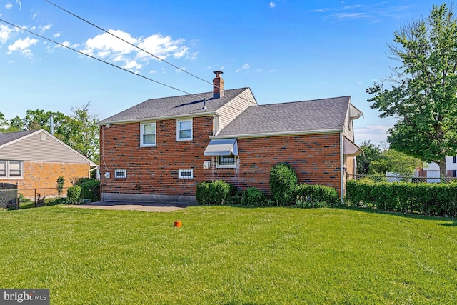 rear view of house with a chimney, brick siding, a shingled roof, and a patio