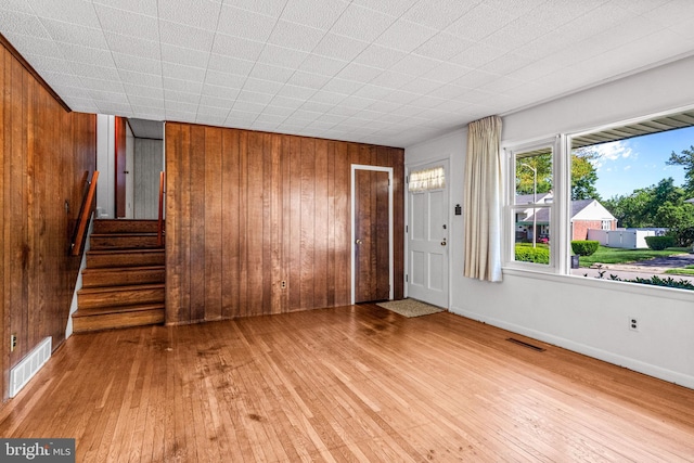 foyer entrance featuring wood walls, hardwood / wood-style flooring, stairway, and baseboards
