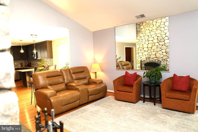 2616 Osage St, Hyattsville, MD 20783 - living room featuring light wood-type flooring, a stone fireplace, and vaulted ceiling