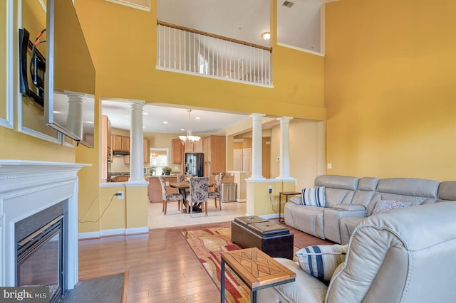 7419 Near Thicket Way, Laurel, MD 20707 - living area featuring ornate columns, light wood finished floors, a glass covered fireplace, baseboards, and a towering ceiling
