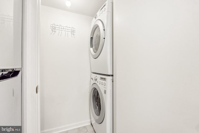 washroom featuring estacked washer and dryer and baseboards
