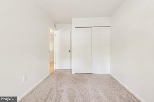 unfurnished bedroom featuring carpet, a closet, and baseboards