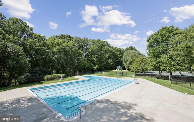 community pool featuring a patio area and view of scattered trees
