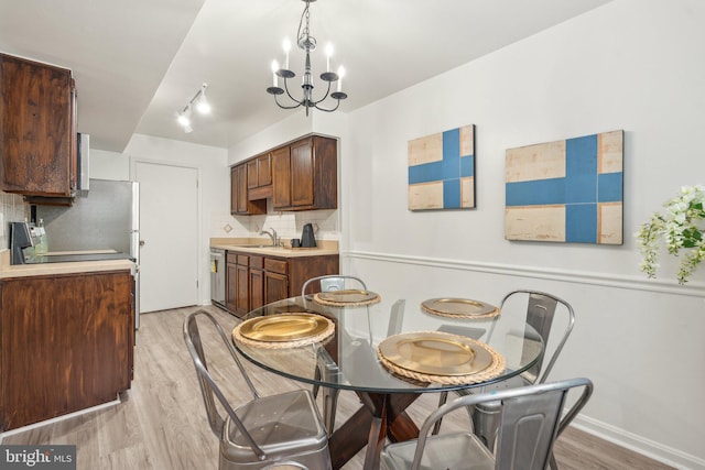 dining room featuring light wood-style floors, a chandelier, and baseboards