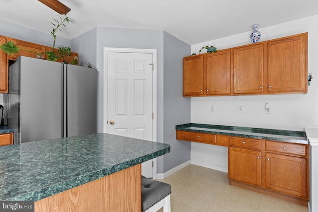 kitchen with freestanding refrigerator, dark countertops, brown cabinets, a breakfast bar, and light floors