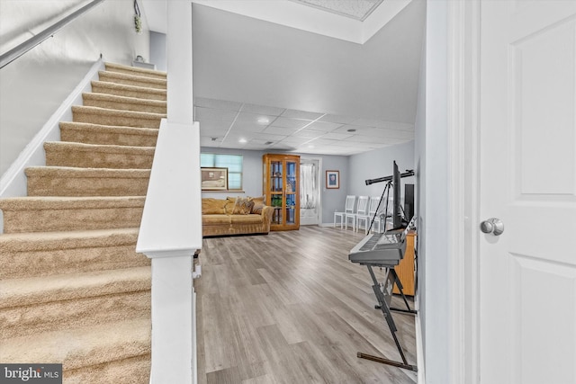 staircase with wood finished floors, a paneled ceiling, and recessed lighting