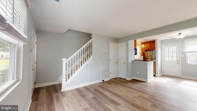 6940 Hawthorne St, Landover, MD 20785 - unfurnished living room featuring stairs, light wood-style floors, healthy amount of natural light, and baseboards