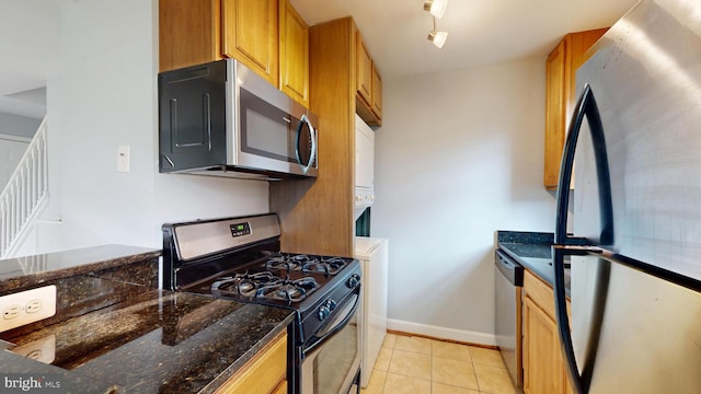 6940 Hawthorne St, Landover, MD 20785 - kitchen with appliances with stainless steel finishes, light tile patterned floors, dark stone countertops, baseboards, and brown cabinets