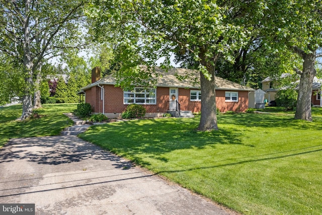 view of front of home featuring brick siding, a chimney, and a front lawn