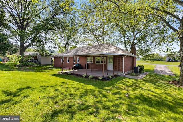 rear view of property featuring a chimney, brick siding, a yard, and central AC unit