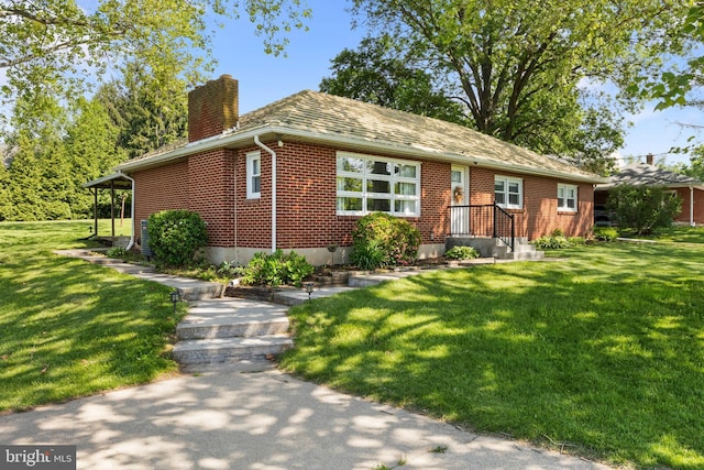 view of front of house featuring a chimney, brick siding, and a front lawn