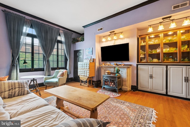 17 W Chase St, Baltimore, MD 21201 - living room featuring ornamental molding, a wood stove, light wood-type flooring, and baseboards