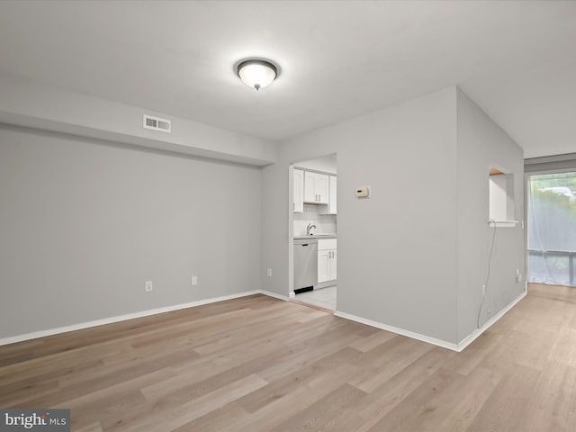 spare room with light wood-style flooring, baseboards, and a sink