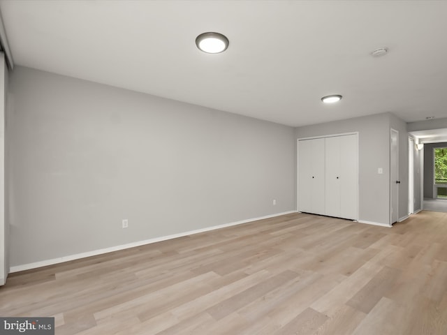 unfurnished bedroom with baseboards, light wood-style flooring, and a closet