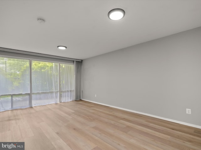 unfurnished room featuring light wood-type flooring, baseboards, and a smoke detector