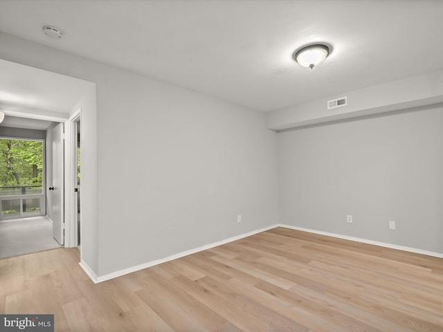 unfurnished room featuring light wood-style floors, a smoke detector, and baseboards