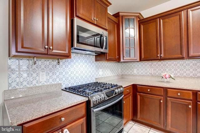 2527 Campus Way N Unit 69, Lanham, MD 20706 - kitchen with appliances with stainless steel finishes, light tile patterned flooring, glass insert cabinets, backsplash, and light stone counters